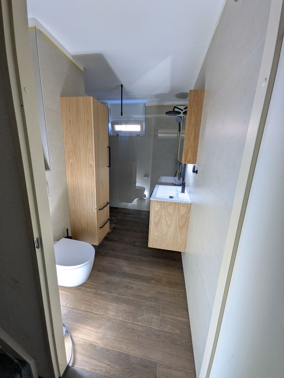 Badkamer met houten meubels en houtlook vloer