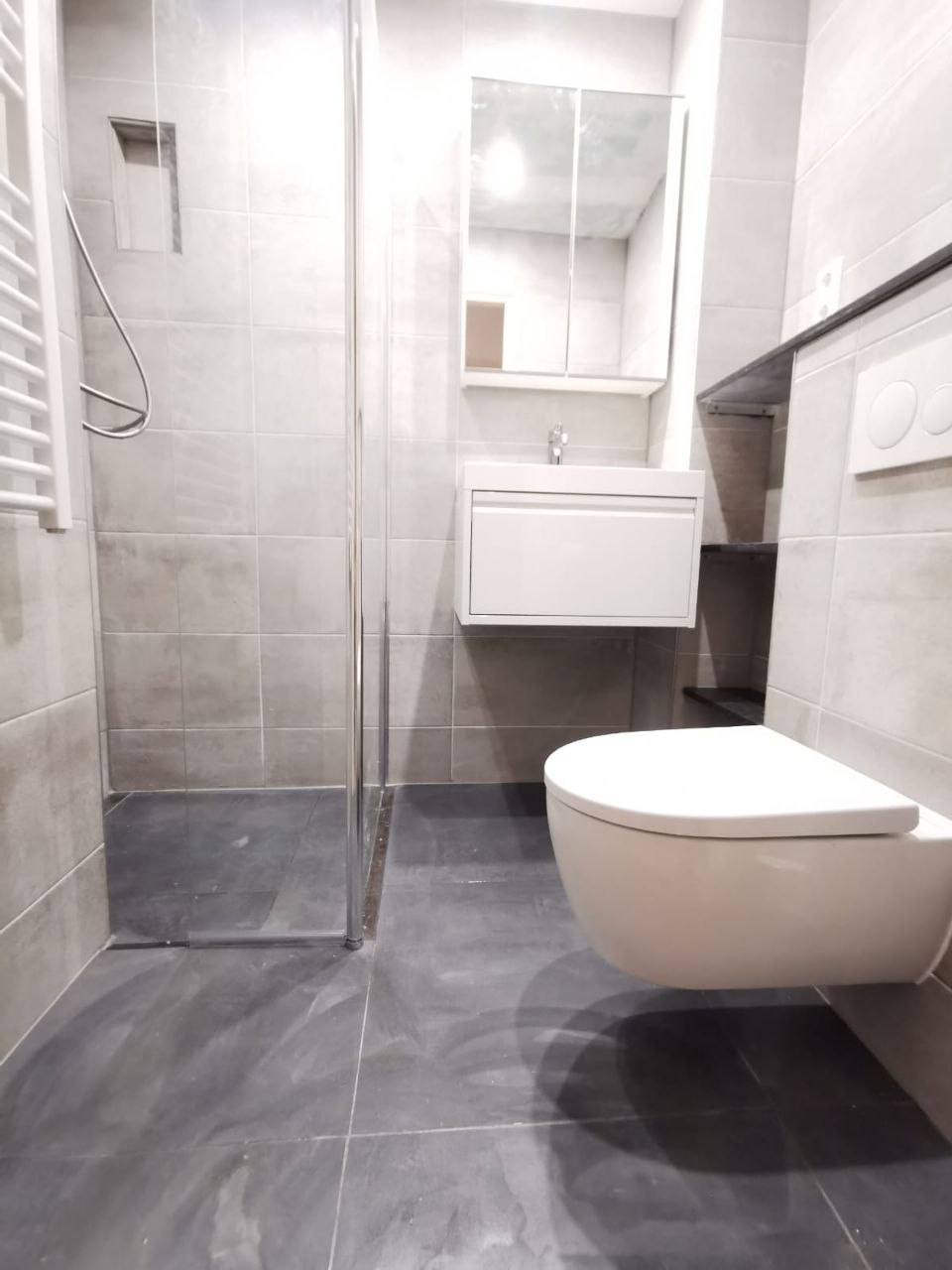 Badkamer met betonlook tegels en zwevend toilet