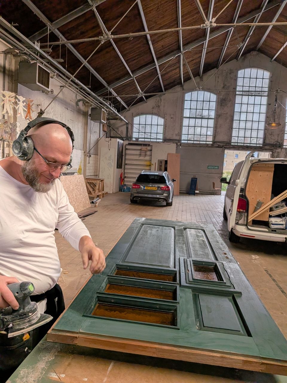 Oude paneeldeur wordt in de werkplaats geschuurd